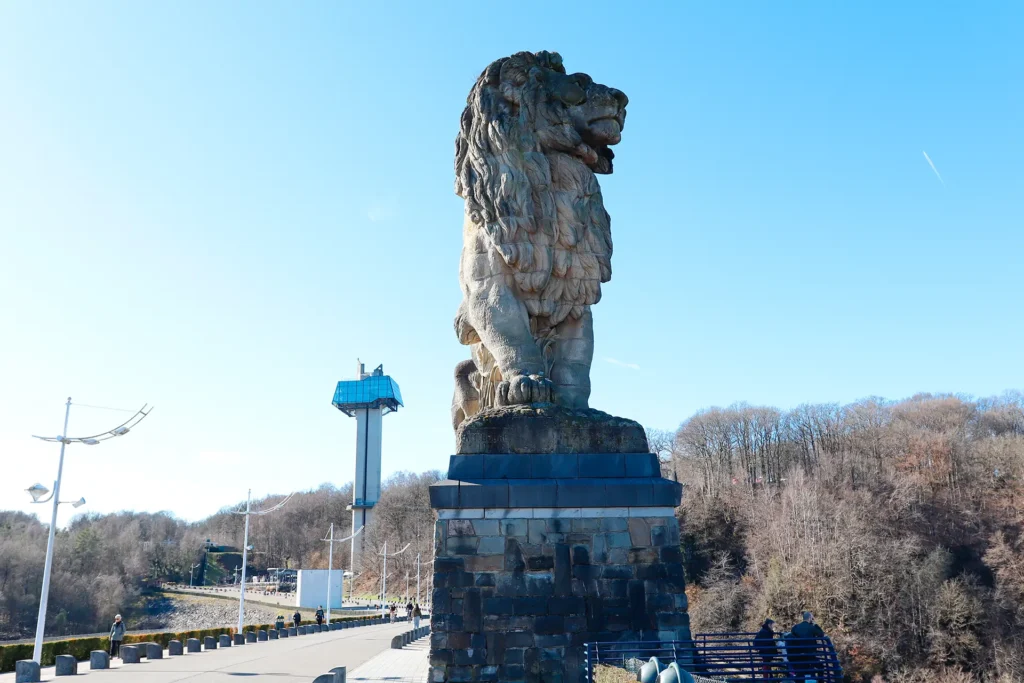 Le lion du barrage de la Gileppe qui trône sur son socle de pierre au sommet du barrage devant la tour panoramique et son restaurant.